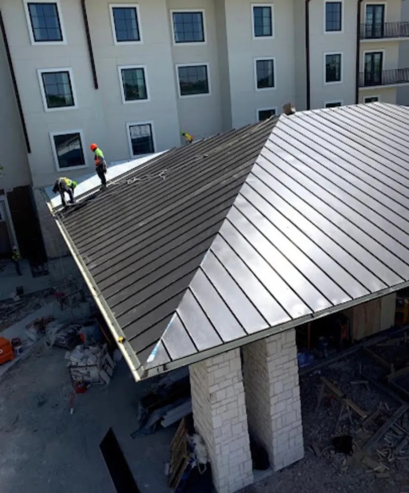 Crew installing standing seam metal roof panels on a commercial project in Jeffersontown
